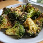Close-up of perfectly roasted broccoli florets topped with crispy Parmesan cheese.