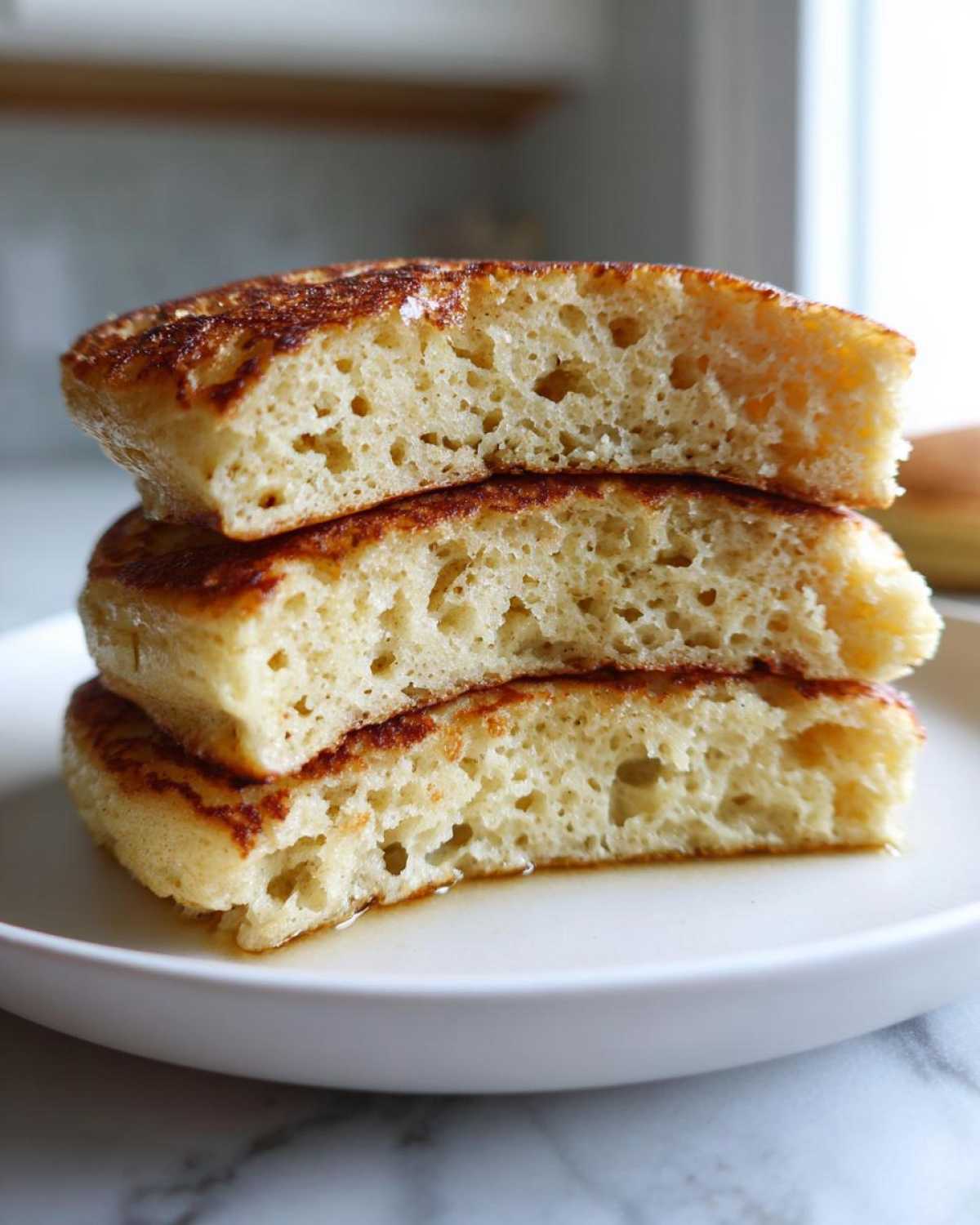 Close-up cross-section of three fluffy almond flour pancakes stacked, showing their light, airy texture.