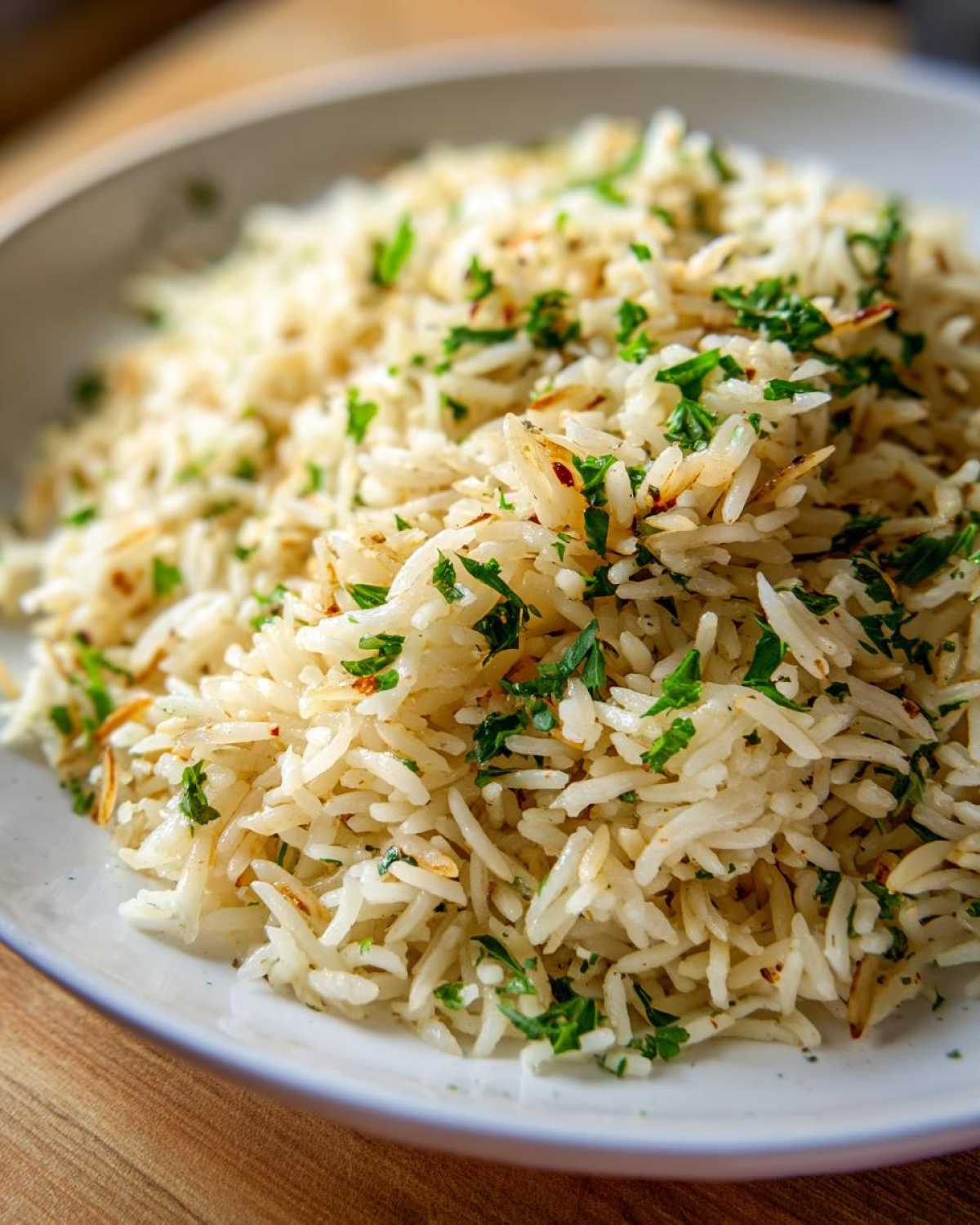 A close-up of fluffy rice pilaf, featuring toasted grains and fresh chopped parsley.
