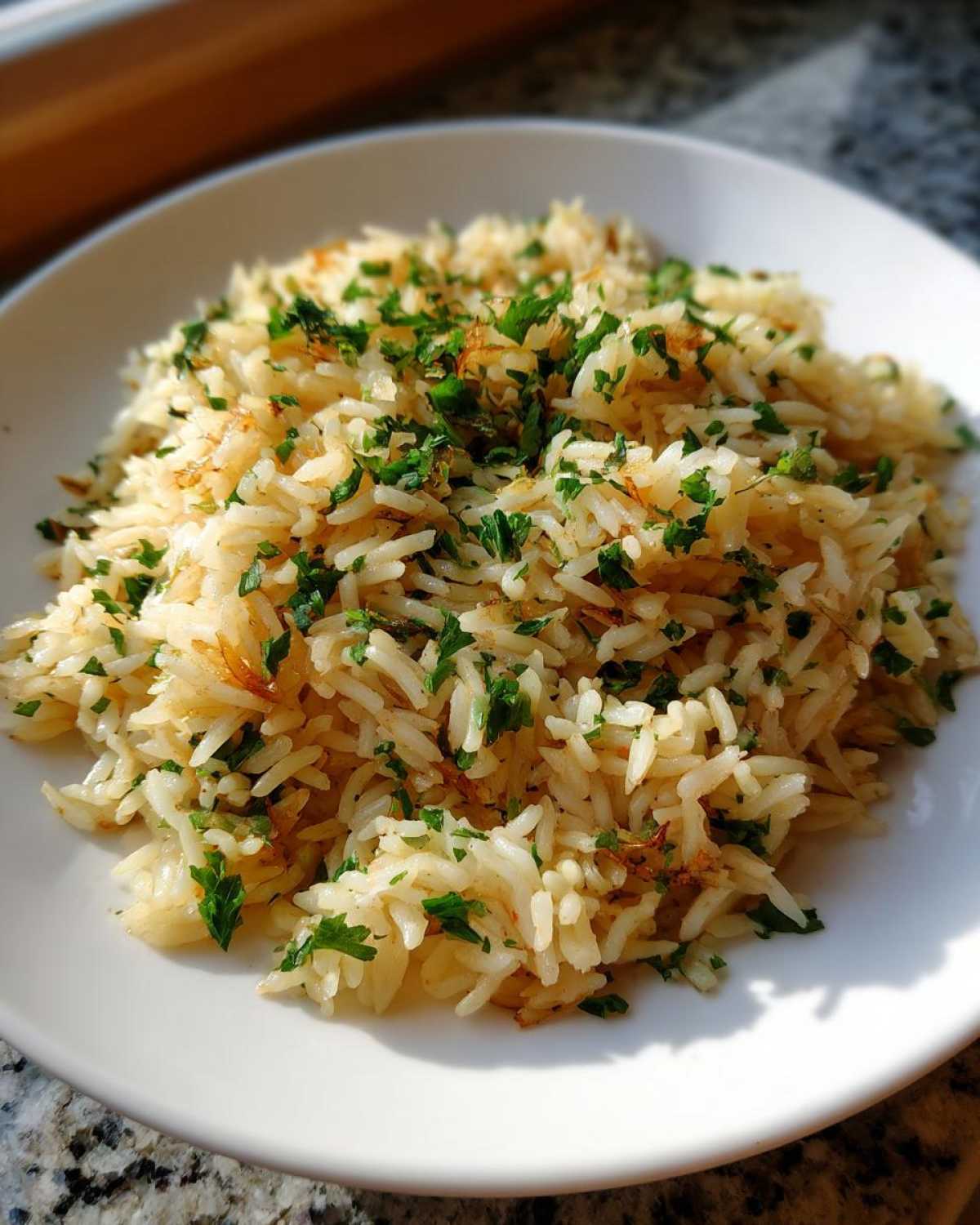 A close-up of fluffy rice pilaf served on a white plate and garnished with chopped green parsley.
