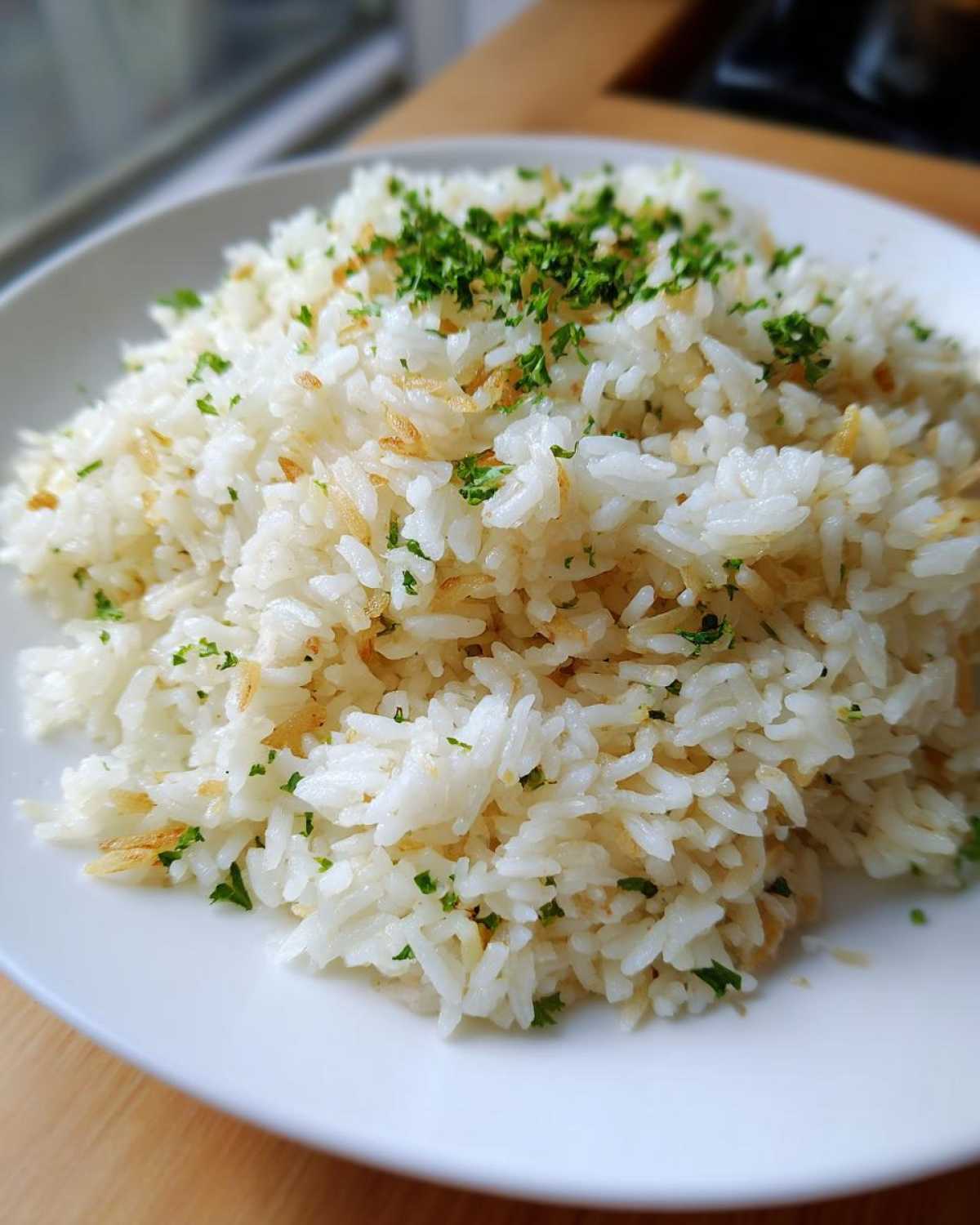 Close-up of fluffy white rice pilaf mixed with toasted vermicelli and topped with fresh parsley.