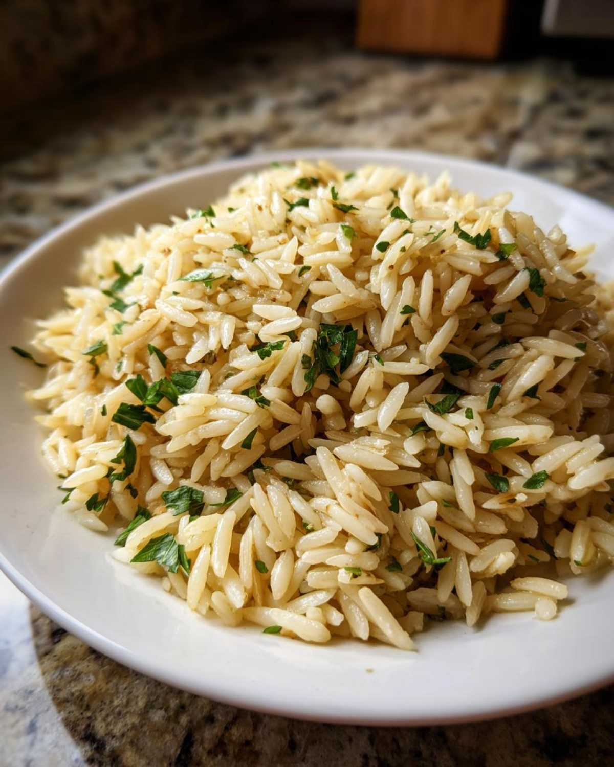 Close-up of fluffy rice pilaf served in a white bowl, garnished with fresh green parsley.