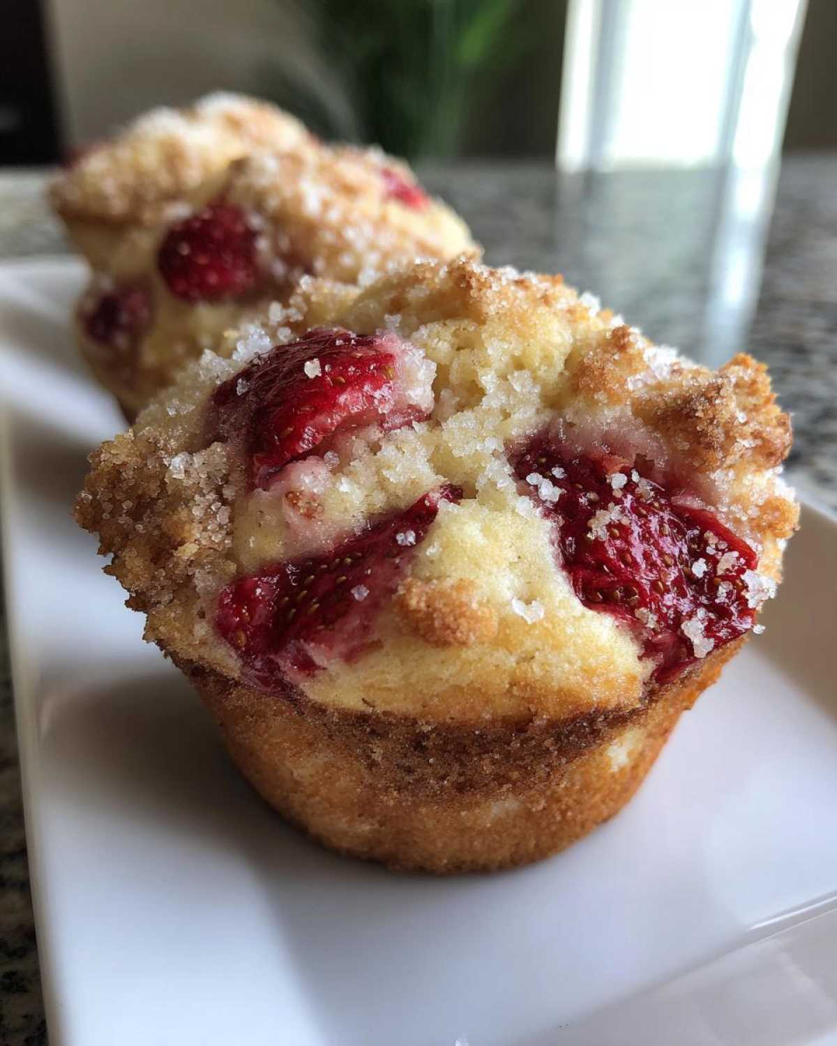 Close-up of a freshly baked, fluffy strawberry muffin topped with large sugar crystals.