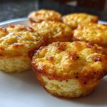 Close-up of several golden brown, fluffy homemade egg bites arranged on a white plate.