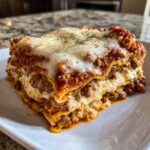 A thick, layered slice of homemade lasagna featuring rich meat sauce and melted cheese topping.