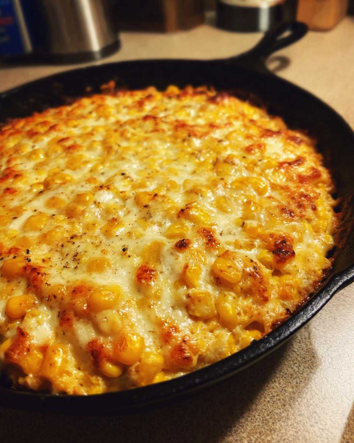 Close-up of hot, cheesy corn dip with cream cheese baked to golden perfection in a cast iron skillet.