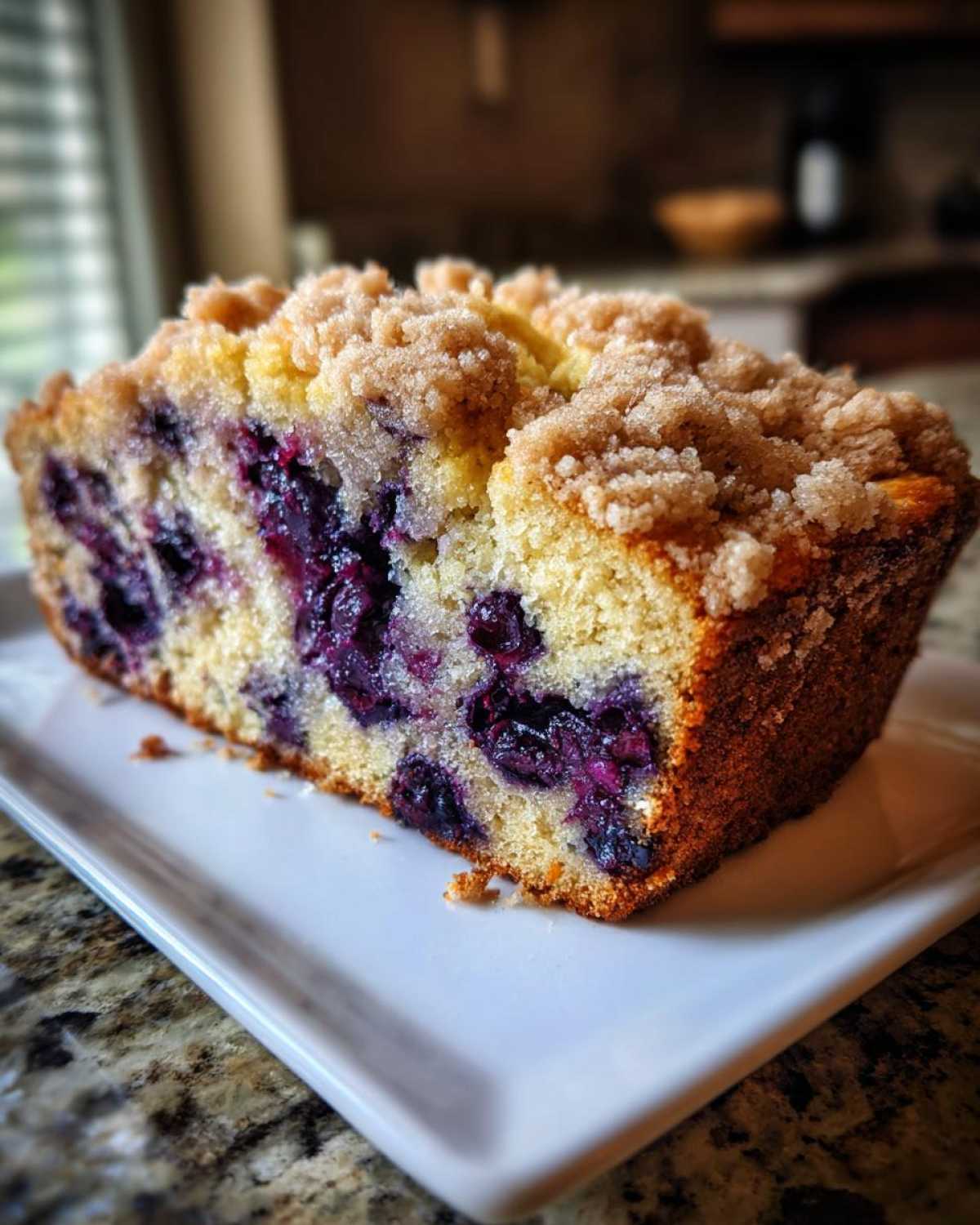 Close-up of a thick slice of moist blueberry banana bread topped with brown sugar streusel.