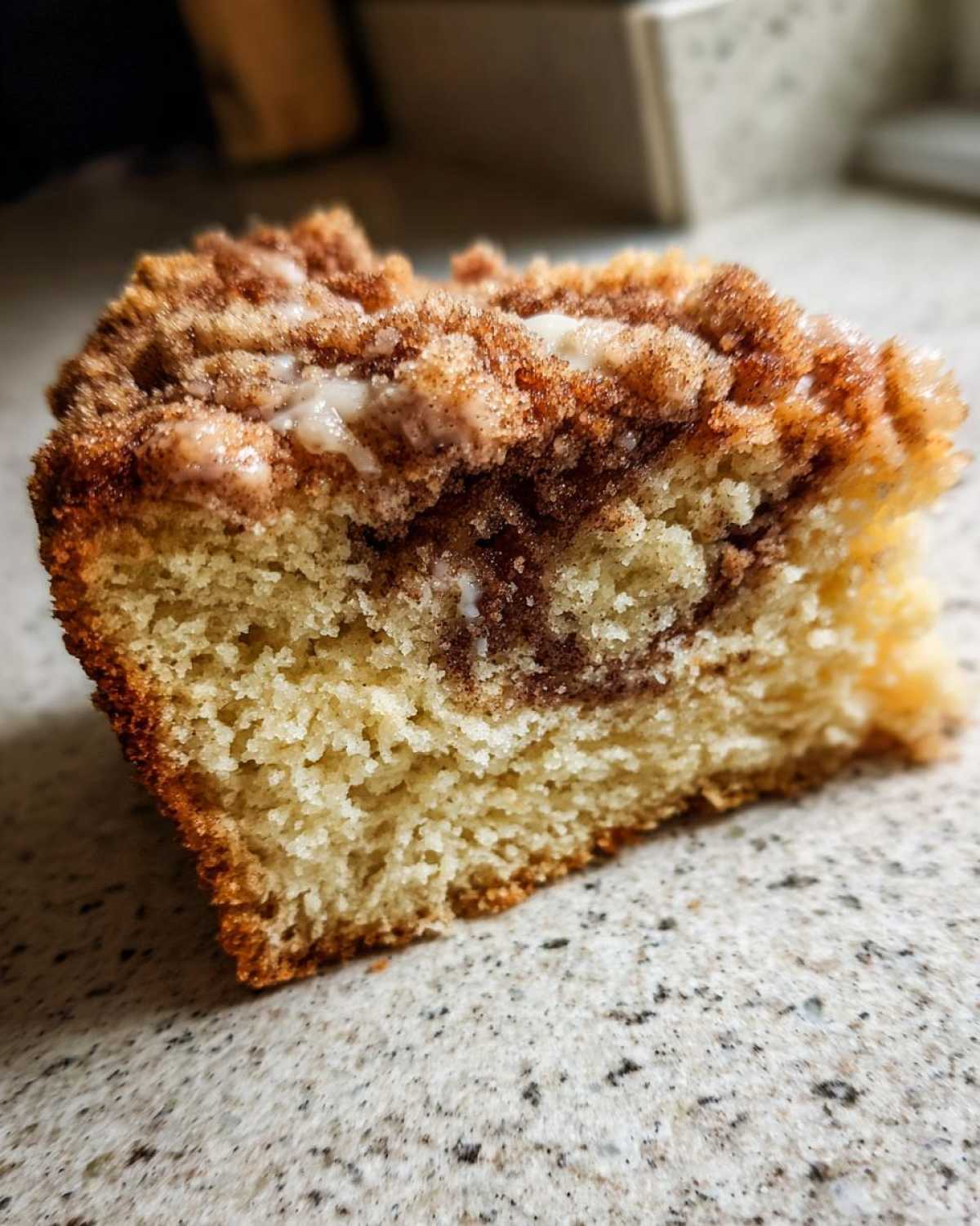 Close-up of a moist slice of sour cream coffee cake showing the tender crumb, cinnamon swirl, and sugary streusel topping.