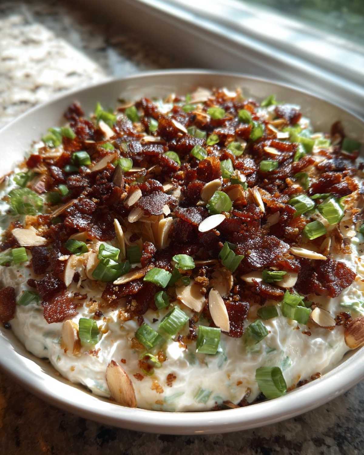 A creamy Neiman Marcus dip topped generously with crumbled bacon, sliced almonds, and chopped green onions.