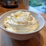 A close-up of thick, creamy Olive Garden Alfredo Sauce topped with black pepper in a white bowl.
