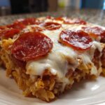 A close-up of a serving of baked pizza pasta, topped with melted mozzarella and pepperoni slices.