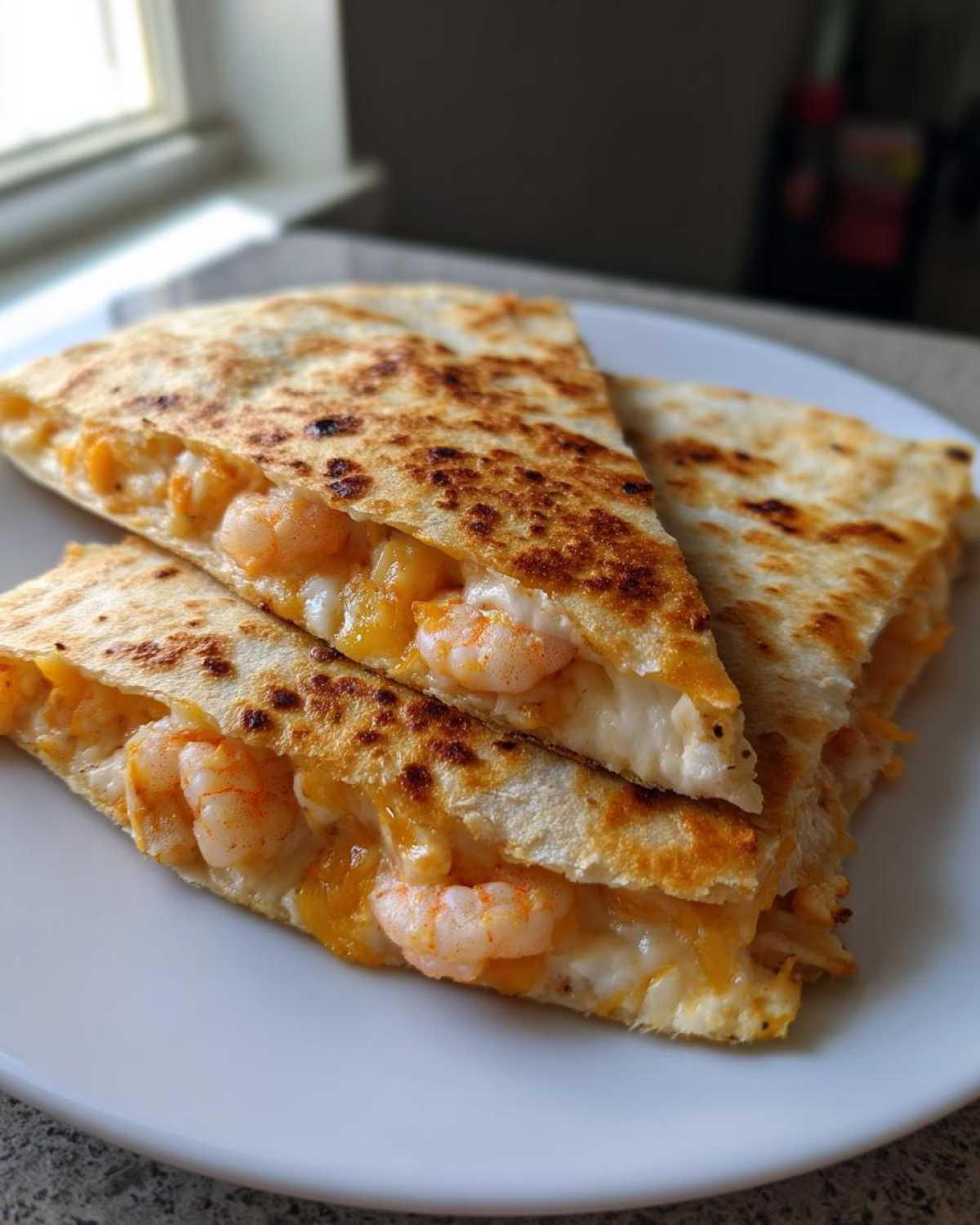 Close-up of three wedges of a perfectly grilled shrimp quesadilla oozing with melted cheese and pink shrimp.