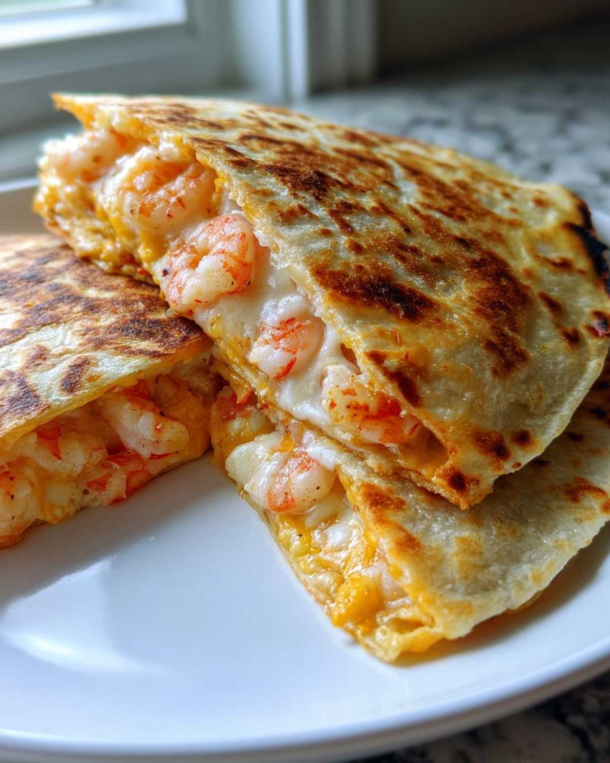 Close-up of a golden-brown shrimp quesadilla cut into wedges, showing melted cheese and plump shrimp filling.