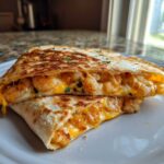 Close-up of a perfectly grilled shrimp quesadilla cut in half, showing melted cheese and seasoned shrimp filling.