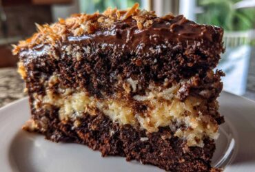 Close-up of a decadent slice of german chocolate cake recipe showing dark layers and coconut pecan frosting.