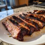 Slices of perfectly grilled steak showing a dark crust and juicy interior, prepared with carne asada marinade.