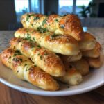 A tempting pile of soft, buttery breadsticks, glistening and topped with Parmesan cheese and fresh parsley.