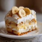 A decadent slice of layered banana pudding topped with whipped cream and fresh banana slices.