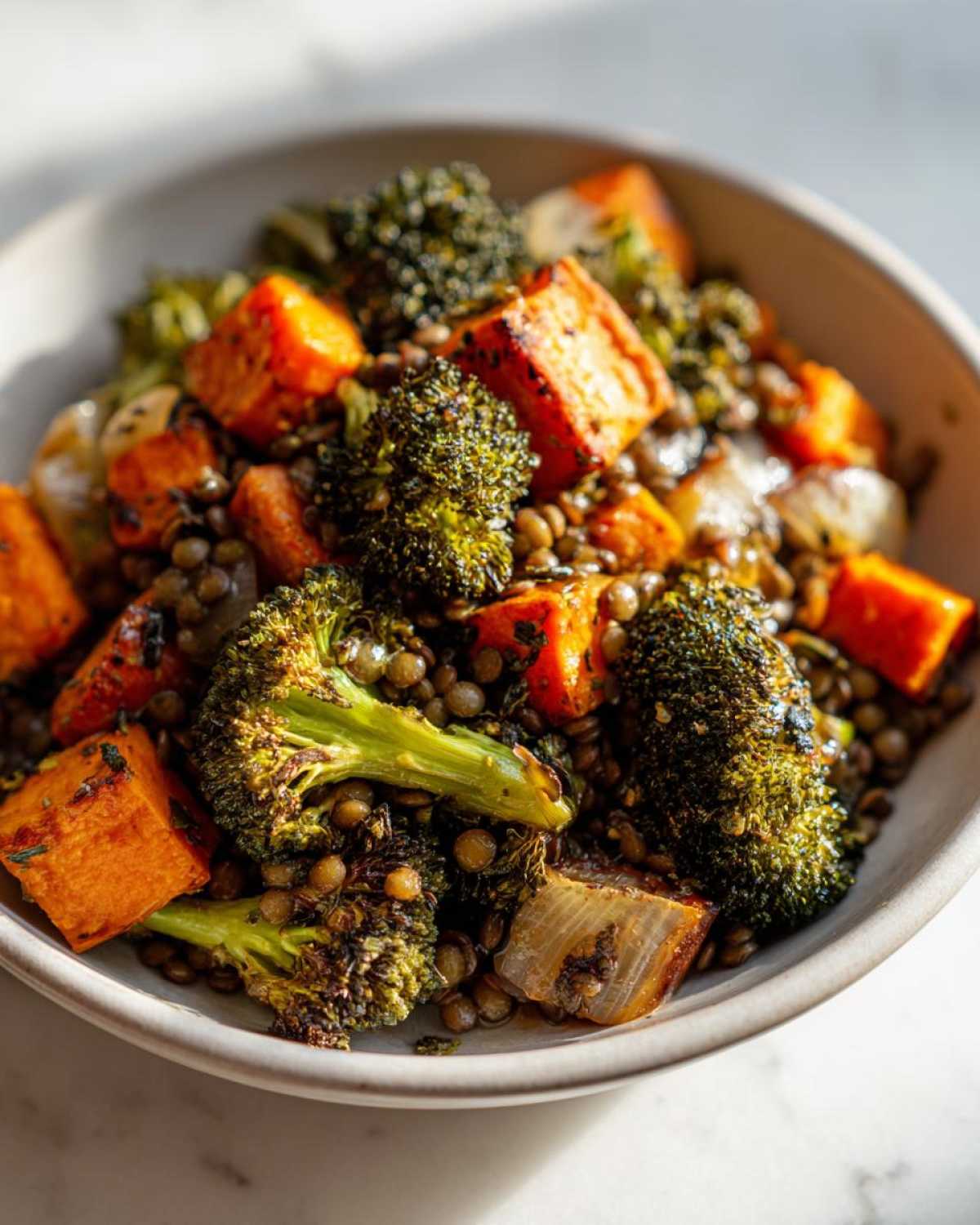 Close-up of a hearty veggie lentil salad featuring roasted broccoli, sweet potato cubes, and lentils in a bowl.