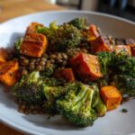 Close-up of a hearty veggie lentil salad featuring roasted sweet potato cubes, green broccoli florets, and brown lentils served on a white plate.