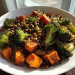 A close-up of a bowl featuring a hearty veggie lentil salad mix with roasted sweet potatoes and broccoli florets.