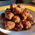 A close-up shot of a white plate piled high with freshly cooked, browned Air Fryer Italian Meatballs.