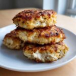 A stack of three perfectly cooked Air Fryer Salmon Patties showing a flaky interior and golden-brown crust.