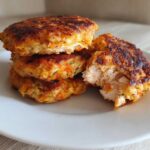 Stack of golden brown Air Fryer Salmon Patties, one broken open showing flaky interior.