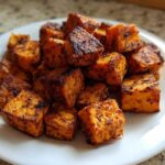 A pile of seasoned and perfectly crispy Air Fryer Sweet Potato Cubes served on a white plate.
