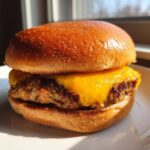 Close-up of a juicy Air Fryer Turkey Burger topped with melted cheddar cheese on a brioche bun.