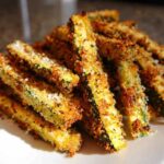 A pile of golden brown, crispy Air Fryer Zucchini Fries with Parmesan cheese sprinkled on top.