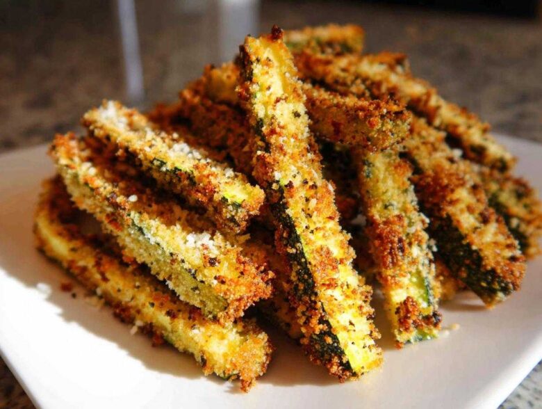 A pile of golden brown, crispy Air Fryer Zucchini Fries with Parmesan cheese sprinkled on top.