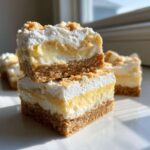 Two stacked squares of Banana Pudding Cheesecake Bars showing graham cracker crust, creamy filling, and whipped topping.
