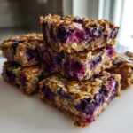 A stack of five moist Blueberry Baked Oatmeal Squares showing visible oats and bursting blueberries.