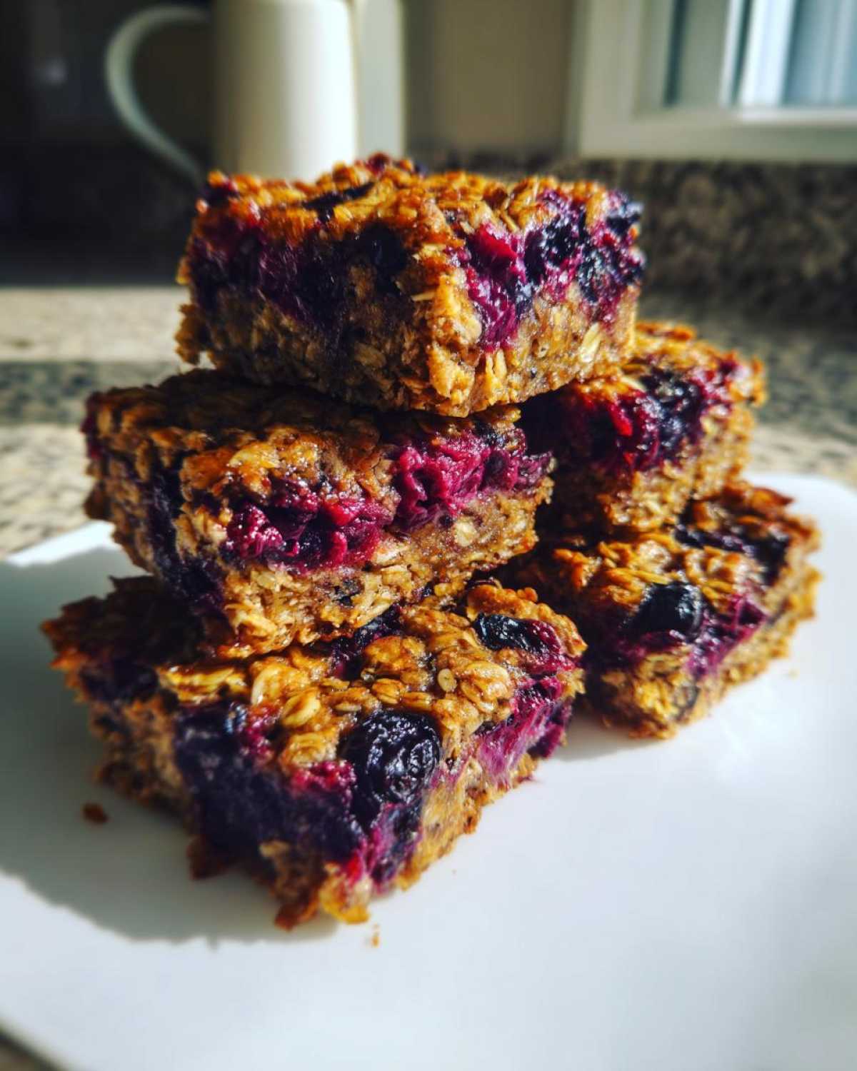 A stack of five moist Blueberry Baked Oatmeal Squares featuring visible oats and deep purple berries.