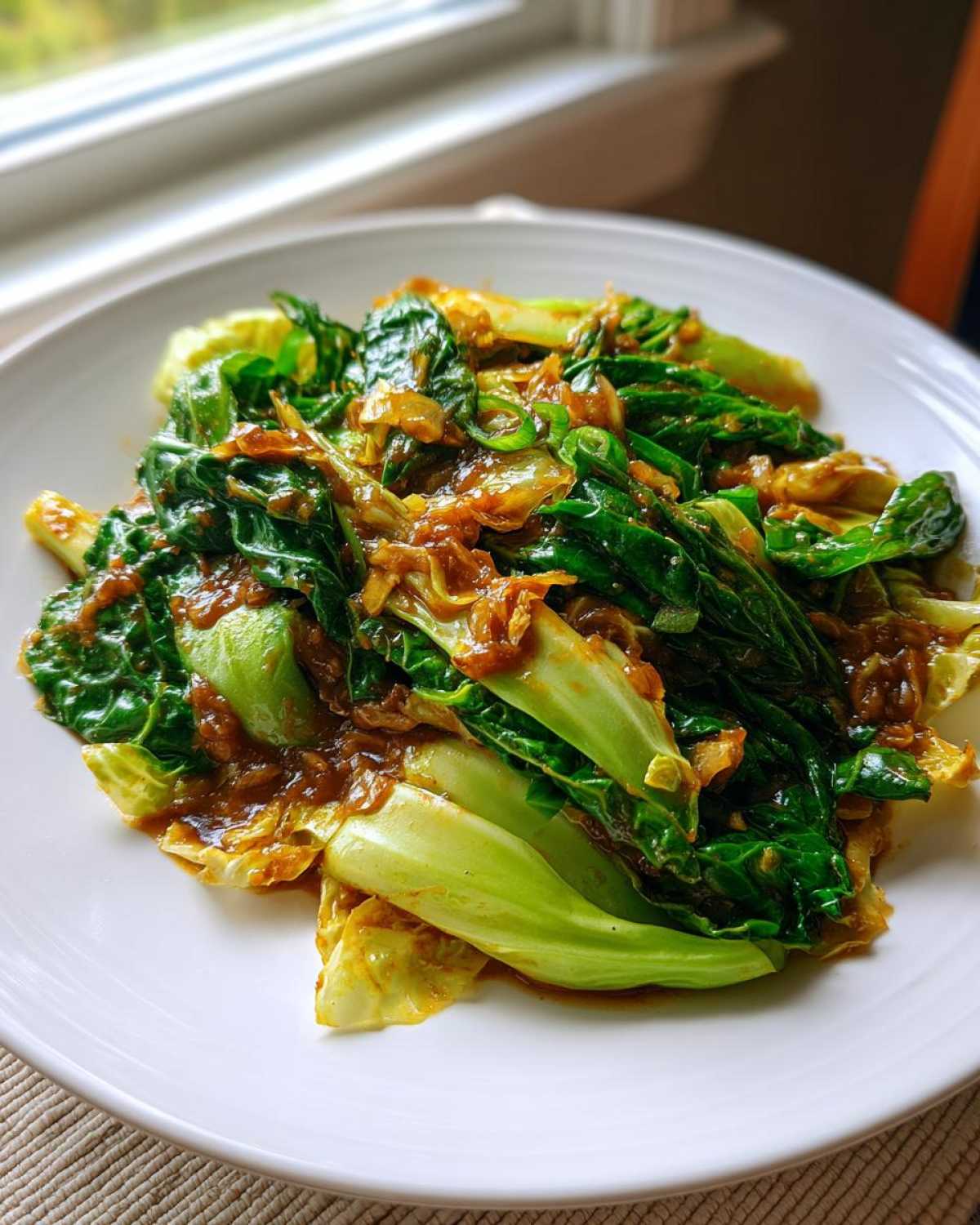 Close-up of vibrant green bok choy and cabbage in a rich Garlic Ginger Sauce, ready for serving.