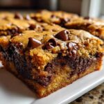 A close-up view of a thick, chewy chocolate chip cookie bars slice showing a gooey center and melted chocolate chips.