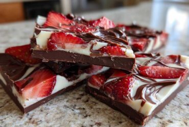 Close-up of stacked pieces of Chocolate Covered Strawberry Bark featuring dark chocolate, white chocolate swirl, and fresh strawberry slices.
