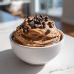 A white bowl filled with rich Chocolate Peanut Butter Cheesecake Dip, swirled with chocolate and topped generously with mini chocolate chips.