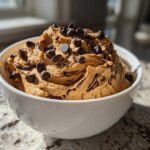 A close-up of creamy Chocolate Peanut Butter Cheesecake Dip topped with mini chocolate chips in a white bowl.
