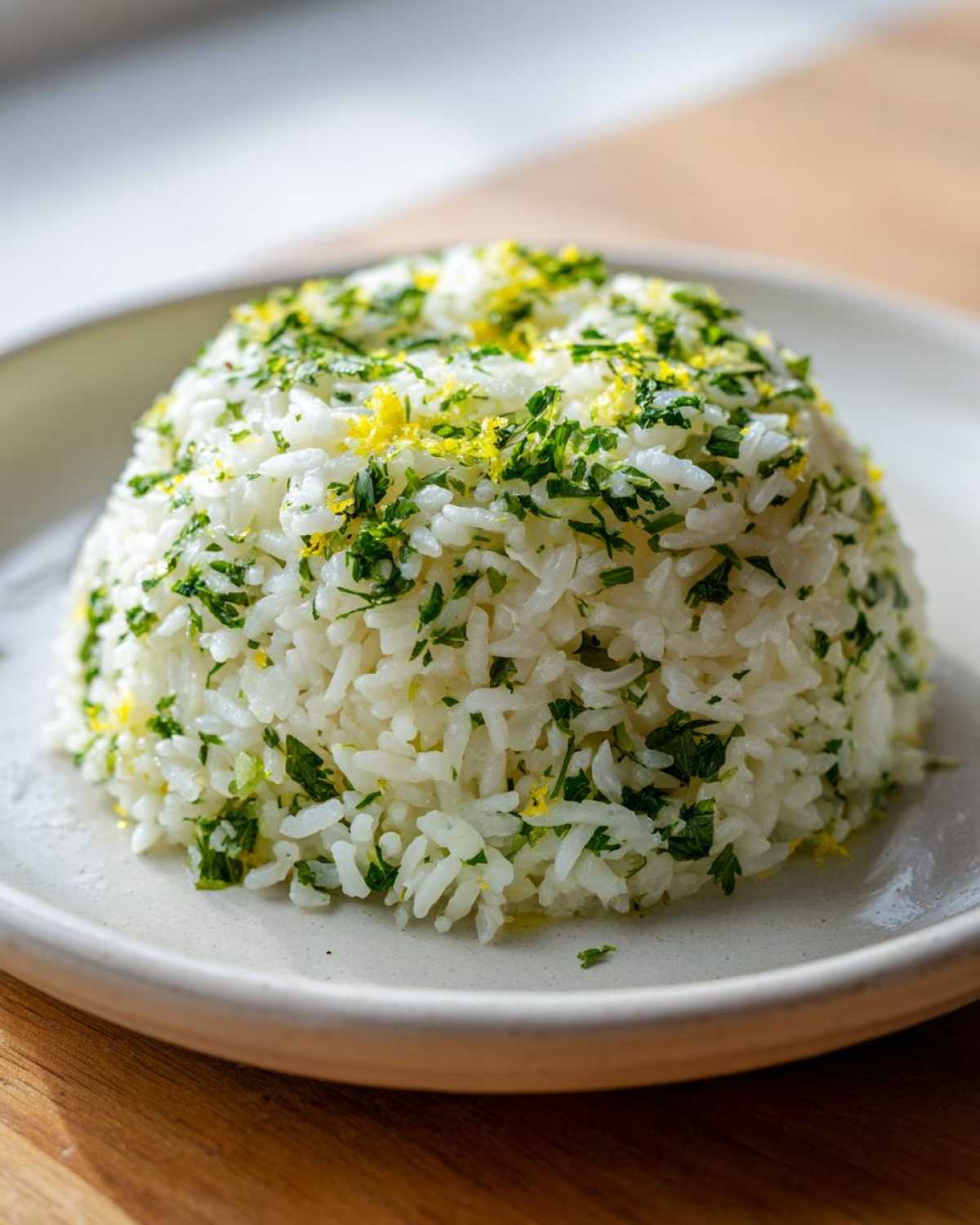 A perfectly molded dome of fluffy white Cilantro Lime Rice topped with chopped cilantro and bright yellow lime zest.