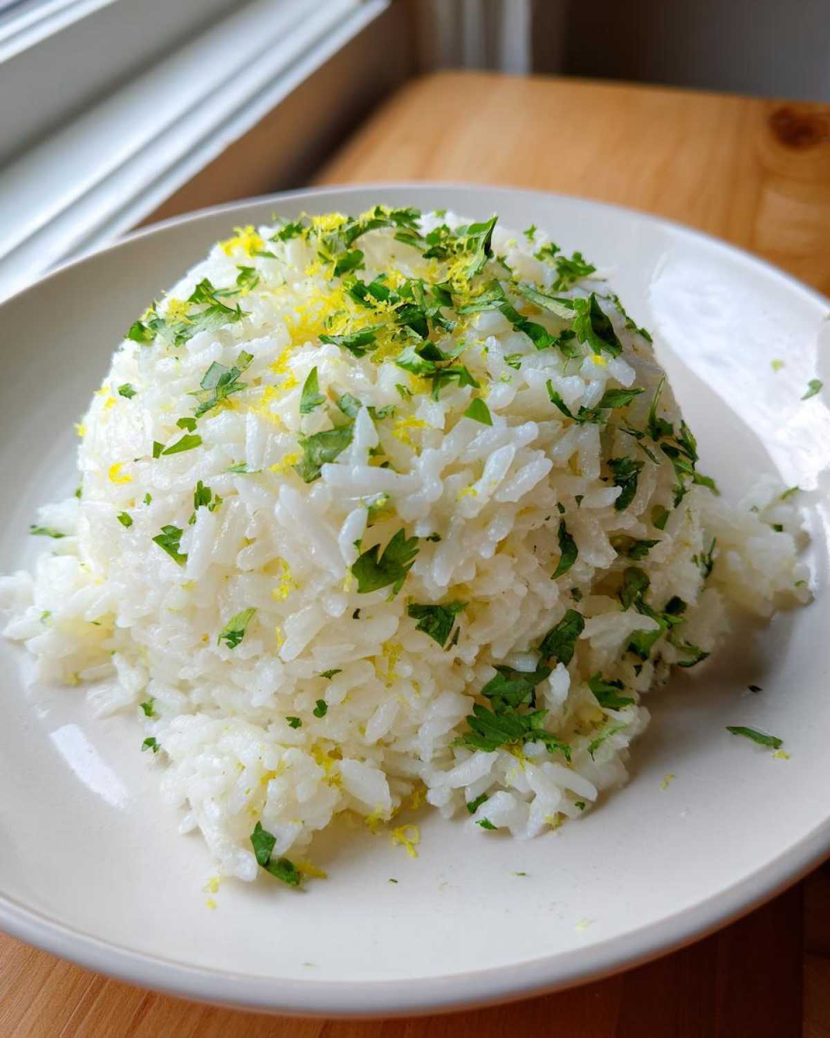 A mound of fluffy white rice topped with chopped cilantro and bright yellow lime zest, perfect for Cilantro Lime Rice for Burrito Bowls.