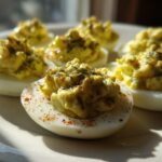 Close-up of several Classic Deviled Eggs with Dill Pickle Relish, piped high and sprinkled with paprika.