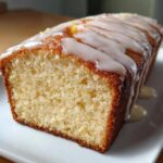 Close-up of a moist slice of Copycat Starbucks Iced Lemon Loaf showing the crumb and thick white lemon glaze.