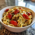 Close-up of a white bowl filled with creamy Baked Feta Pasta with Cherry Tomatoes, garnished with fresh parsley.