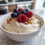 A thick, creamy vanilla protein smoothie bowl topped with fresh raspberries, blueberries, and granola.