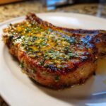 Close-up of a perfectly cooked, juicy Crispy Air Fryer Pork Chop glazed with melted garlic butter and herbs.