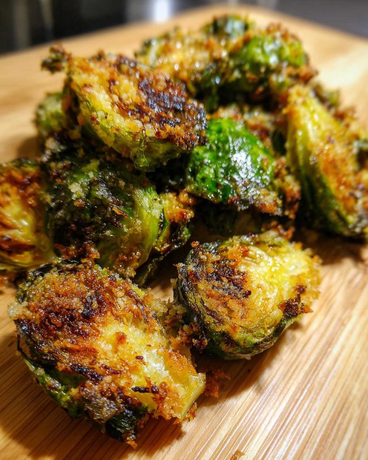 Close-up of halved, roasted Crispy Parmesan Brussels Sprouts with a golden-brown, crunchy topping.