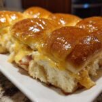 A row of freshly baked Hawaiian Roll Ham and Cheese Sliders covered in a shiny honey mustard glaze.