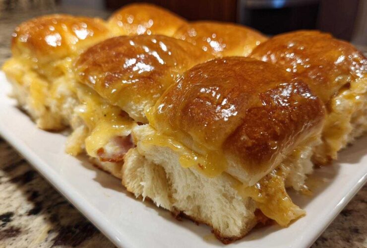 A row of freshly baked Hawaiian Roll Ham and Cheese Sliders covered in a shiny honey mustard glaze.